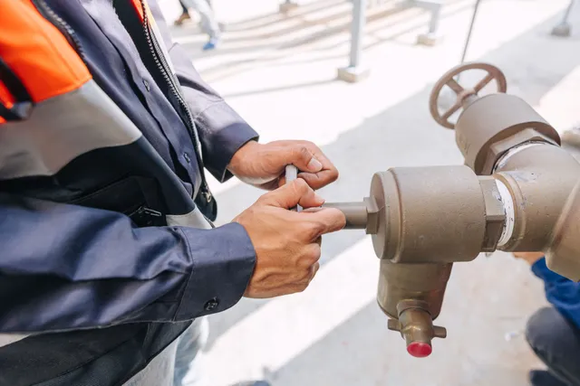 A man is adjusting a valve on a pipe.